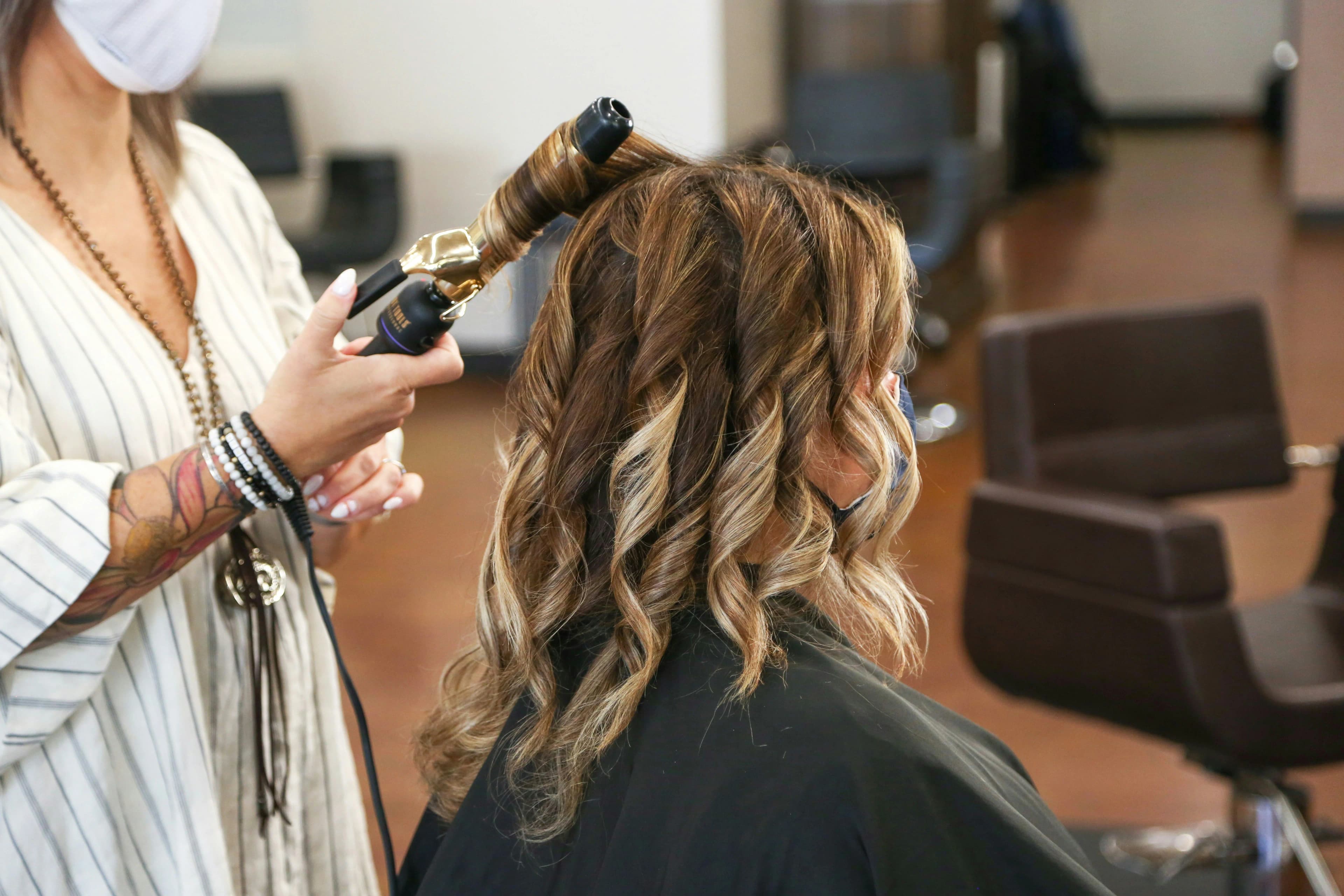 Stylist curling a client's hair in studio